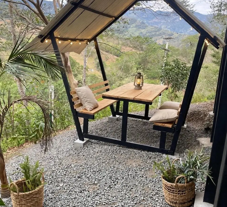 Covered table and benches on gravel, looking out over the mountains